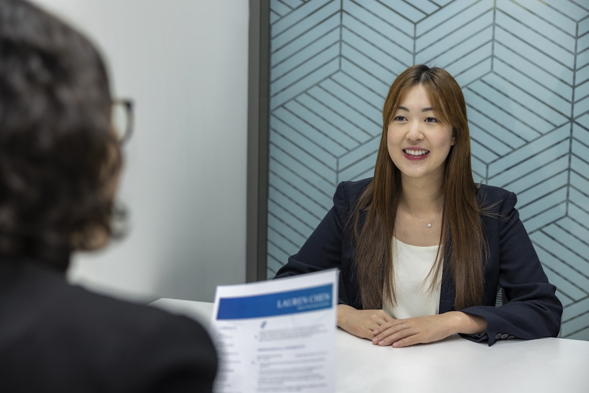 밝고 모던한 오피스 회의실에서 외국인 면접관들과 웃으며 악수하는 자신감 넘치는 여성