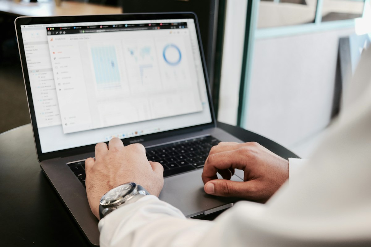 세련된 디자인의 고해상도 모니터 앞에 앉아 복잡한 데이터 차트와 영문 이력서 초안을 면밀히 분석하며 펜으로 메모를 남기는 커리어 컨설턴트의 손