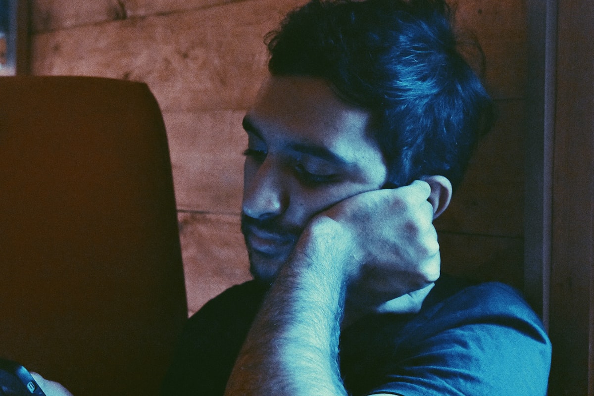 어두운 방 안에서 노트북 화면의 복잡한 텍스트를 응시하며 눈을 비비고 있는 피곤한 기색의 중년 남성 지원자
